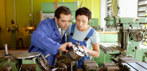 Man and woman in technology workshop, adjusting machine chuck --- Image by © Ocean/Corbis
